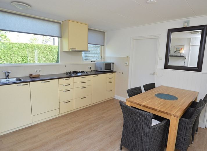 Gemuetliches Wohnzimmer des Ferienhauses de Parel 282, De Dennen, Texel, mit Blick auf den gruenen Garten.