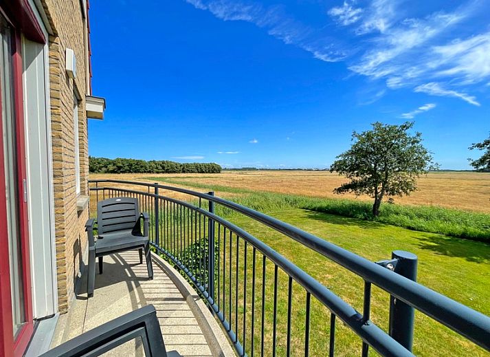 Lichte woonkamer in Appartement Bos en Duin 43 op Texel met comfortabele meubels en toegang tot het balkon.