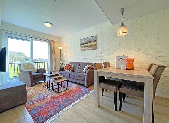 Gemuetliches Wohnzimmer des Appartements Bos en Duin 31 in De Dennen, Texel mit bequemer Sitzecke und Blick auf die Natur.