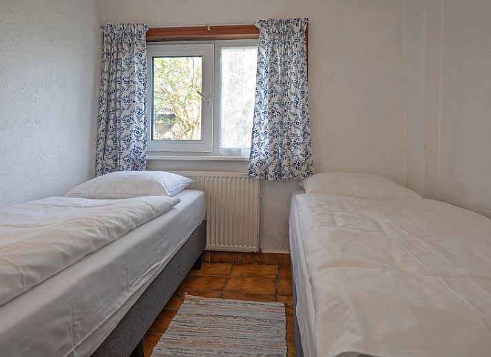 Veranda des Ferienhauses Duumpie in De Dennen, Texel mit Sitzgelegenheiten und gruener Umgebung.