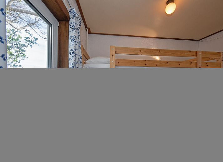 Veranda des Ferienhauses Duumpie in De Dennen, Texel mit Sitzgelegenheiten und gruener Umgebung.