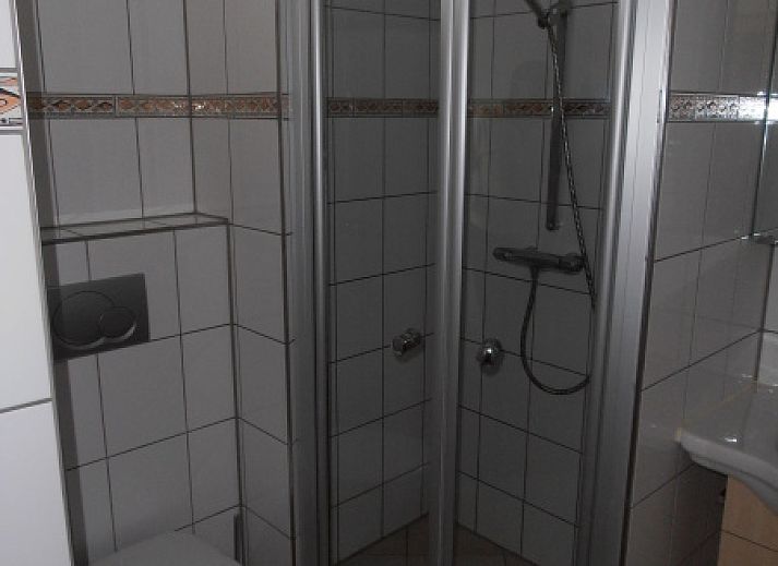 Geraeumiger Garten des Ferienhauses Gortersmient 298, De Dennen, Texel mit Rasen und Schuppen.