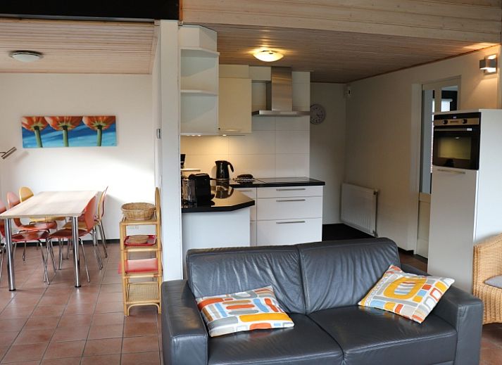 Gemuetliches Wohnzimmer im Ferienhaus Gortersmient 324, De Dennen, Texel mit moderner Kueche und gemuetlicher Sitzecke.