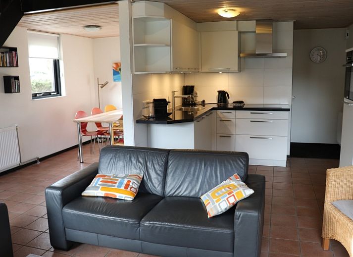 Gemuetliches Wohnzimmer im Ferienhaus Gortersmient 324, De Dennen, Texel mit moderner Kueche und gemuetlicher Sitzecke.