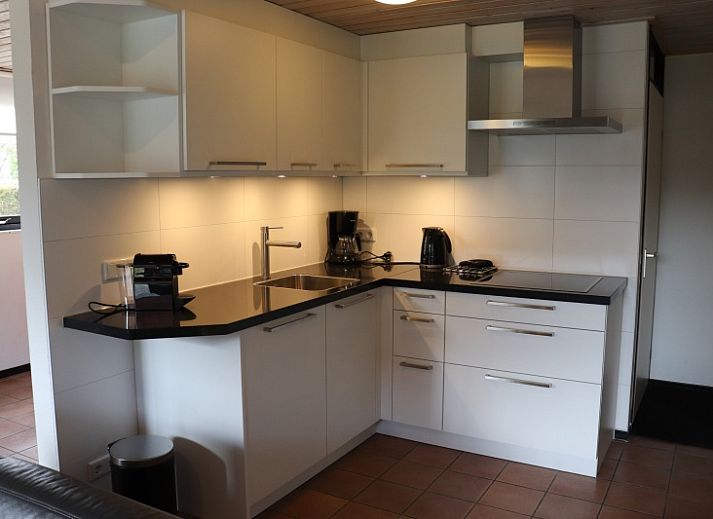 Gemuetliches Wohnzimmer im Ferienhaus Gortersmient 324, De Dennen, Texel mit moderner Kueche und gemuetlicher Sitzecke.