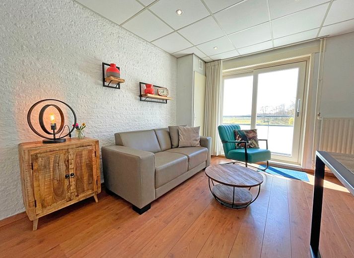 Gemuetliches Wohnzimmer im Apartment Bos en Duin 18, De Dennen, Texel mit bequemem Sofa und Blick auf die Natur.