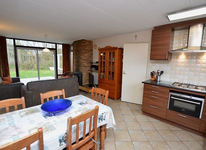 Gezellige woonkamer van Vakantiehuis de Parel 160 in De Dennen, Texel, met uitzicht op de groene omgeving en een knusse open haard.