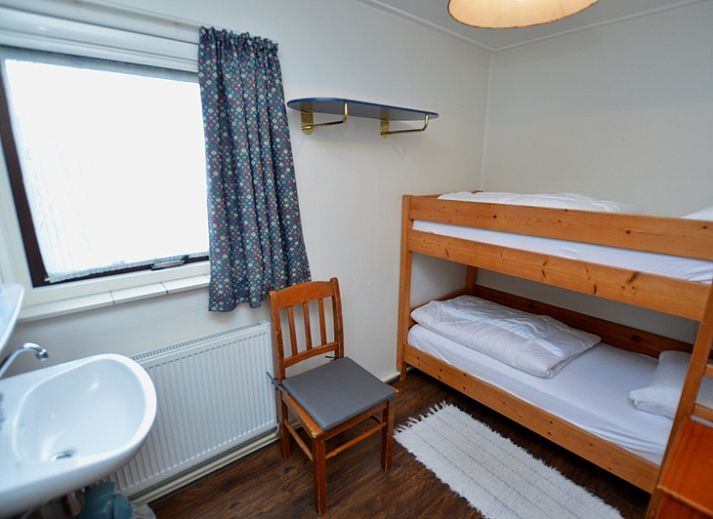 Gezellige woonkamer van Vakantiehuis de Parel 160 in De Dennen, Texel, met uitzicht op de groene omgeving en een knusse open haard.