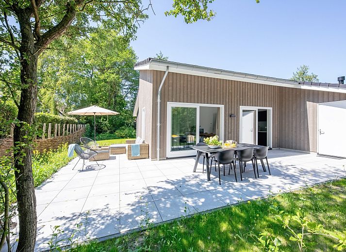 Geniet van de zonnige patio van vakantiehuis Tormentil in De Dennen, Texel, omgeven door weelderige natuur.