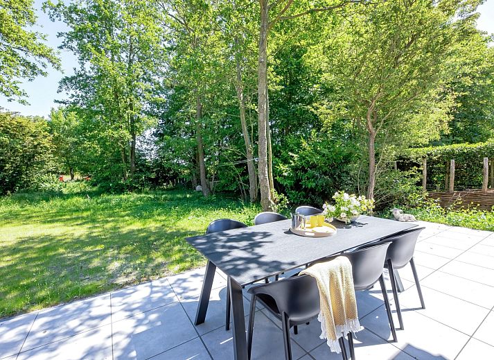 Geniet van de zonnige patio van vakantiehuis Tormentil in De Dennen, Texel, omgeven door weelderige natuur.