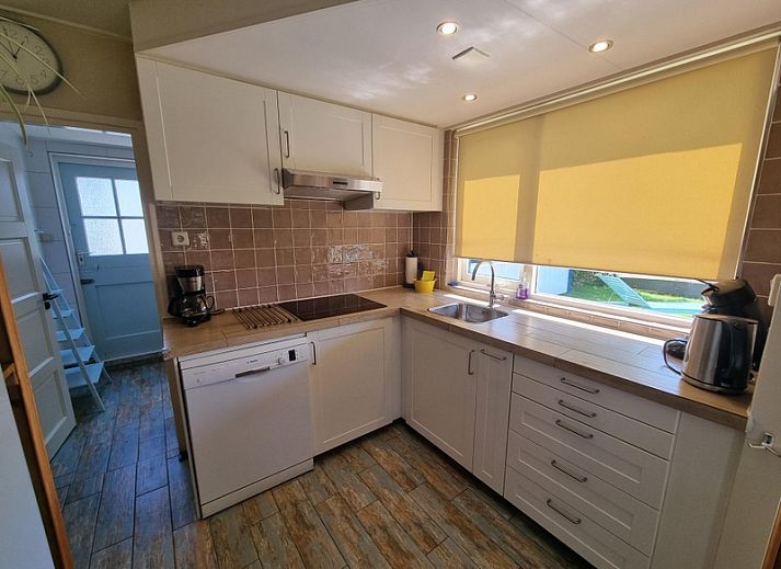 Veranda of Weidezicht vacation home in De Dennen, Texel with deck chairs and lawn.