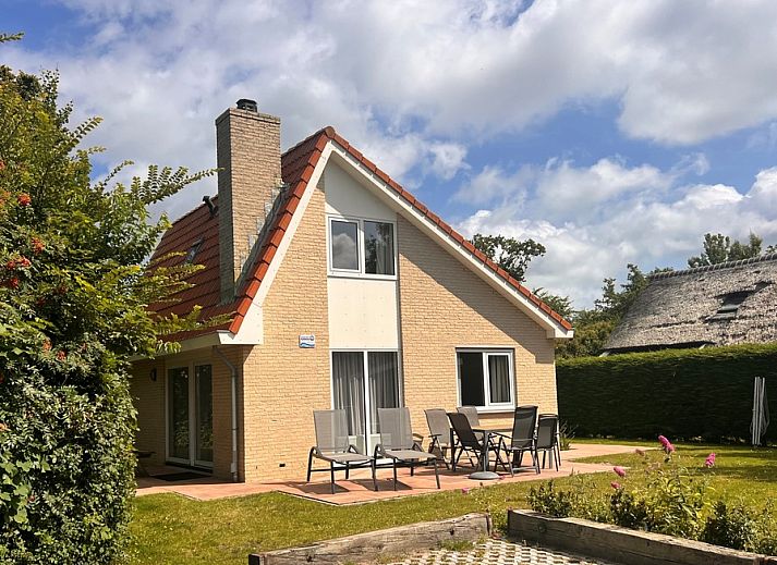 Aussenansicht des Ferienhauses 't Hoogelandt 136 in De Dennen, Texel, mit sonniger Terrasse und gruener Umgebung.