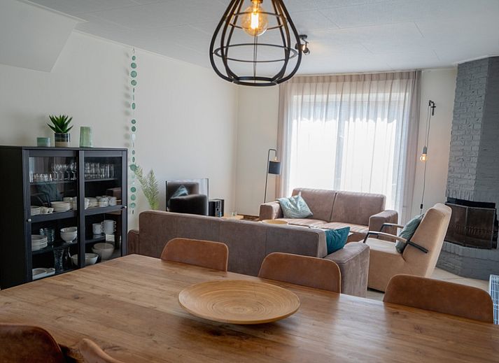 Aussenansicht des Ferienhauses 't Hoogelandt 136 in De Dennen, Texel, mit sonniger Terrasse und gruener Umgebung.