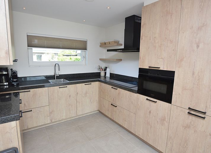 Moderne woonkamer in Tempelierweg - Kogermient 18, De Dennen Texel, met leren banken en open keuken.