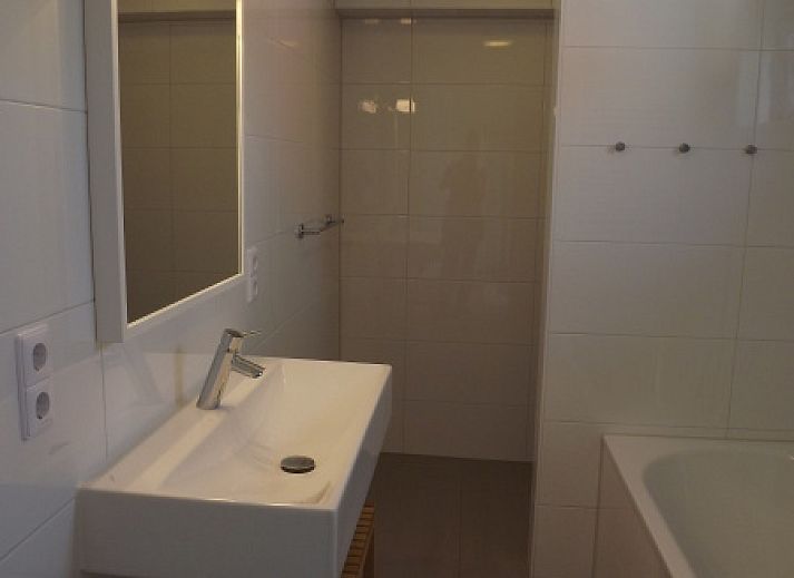 Buitenzijde van Vakantiehuis Gortersmient 320, De Dennen, Texel met comfortabele zithoek en eettafel op het terras, perfect voor buitenleven.