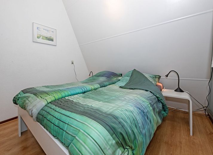 Terras van vakantiehuis Gortersmient 236, Texel, met comfortabele stoelen en parasol, ideaal voor buitenontspanning in De Dennen.