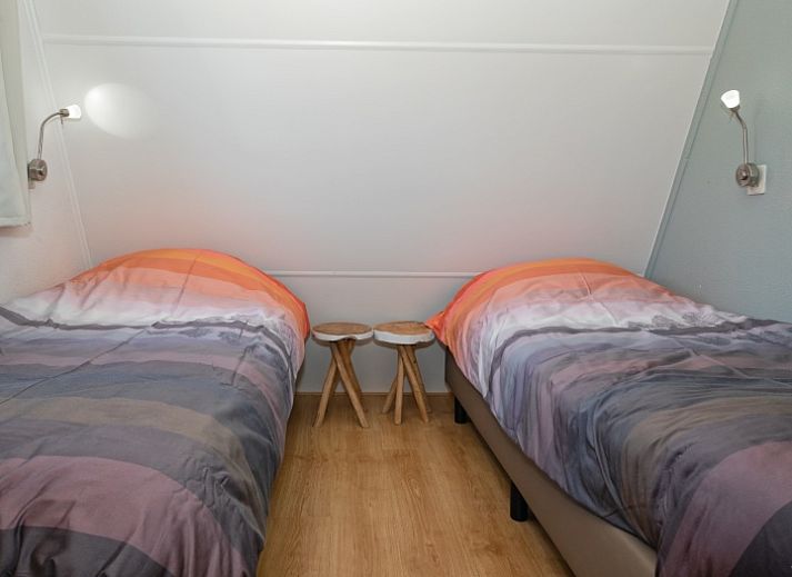 Terras van vakantiehuis Gortersmient 236, Texel, met comfortabele stoelen en parasol, ideaal voor buitenontspanning in De Dennen.