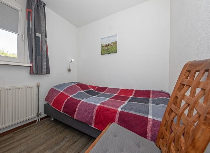 Terras van vakantiehuis Gortersmient 236, Texel, met comfortabele stoelen en parasol, ideaal voor buitenontspanning in De Dennen.