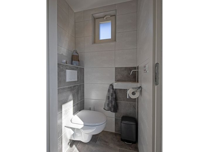 Terras van vakantiehuis Gortersmient 236, Texel, met comfortabele stoelen en parasol, ideaal voor buitenontspanning in De Dennen.