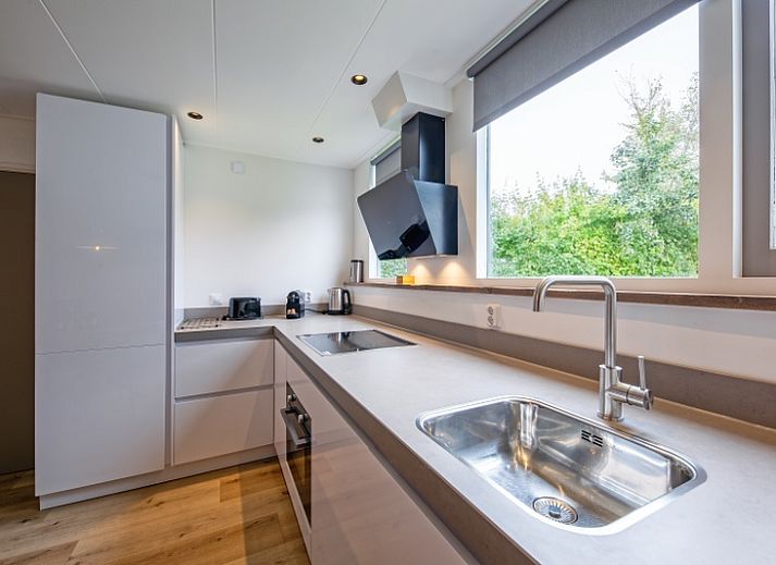 Gezellige woonkamer met open haard in Vakantiehuis de Parel 166, Bungalowpark De Parel, Texel, perfect voor knusse avonden.