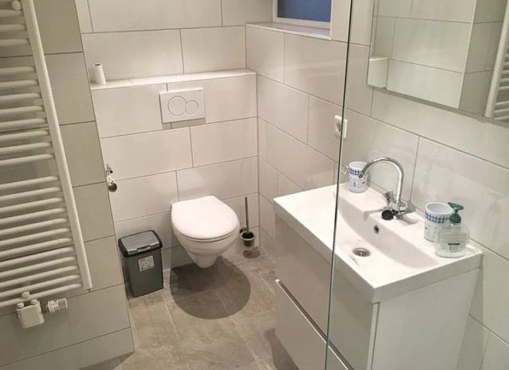 Eetkamer van Bollenveld - de Iris, vakantiehuis in De Dennen, Texel met houten tafel en uitzicht op tuin.