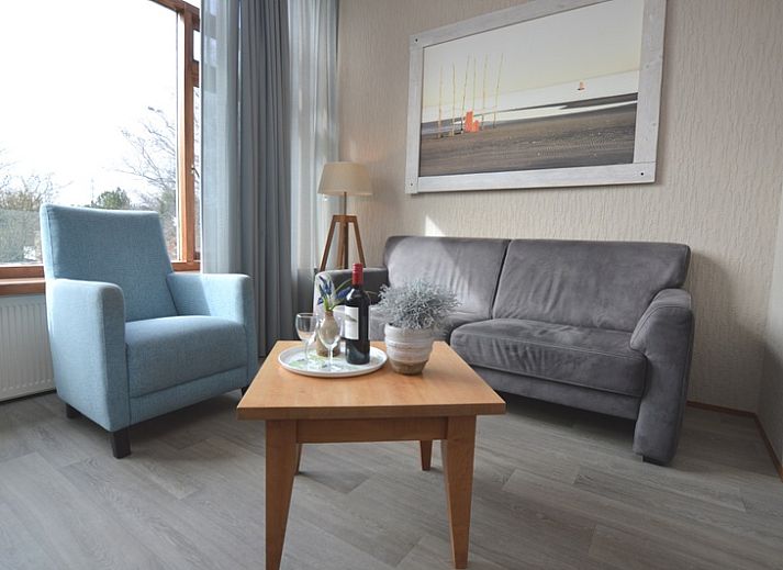 Gemuetliches Wohnzimmer im Ferienhaus Lelie, De Dennen, Texel mit bequemer Sitzecke und grossen Fenstern.