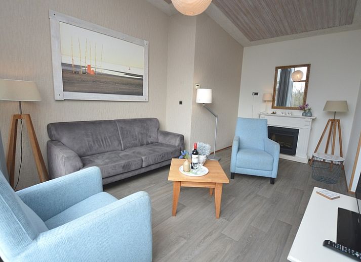 Gemuetliches Wohnzimmer im Ferienhaus Lelie, De Dennen, Texel mit bequemer Sitzecke und grossen Fenstern.