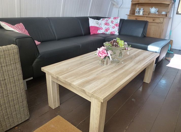 Gezellige woonkamer in Sonnevanck vakantiehuis op Vlieland, Waddeneilanden, met comfortabele zwarte bank.