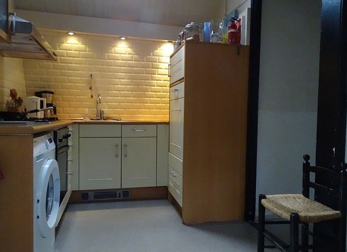 Gezellige woonkamer in Sonnevanck vakantiehuis op Vlieland, Waddeneilanden, met comfortabele zwarte bank.