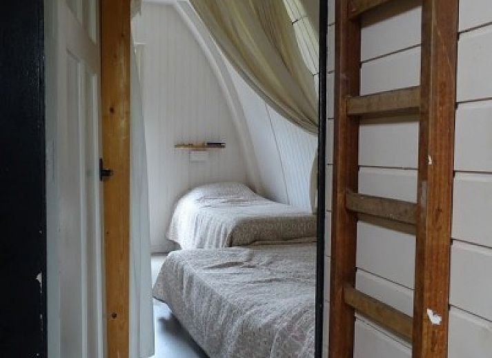 Gezellige woonkamer in Sonnevanck vakantiehuis op Vlieland, Waddeneilanden, met comfortabele zwarte bank.