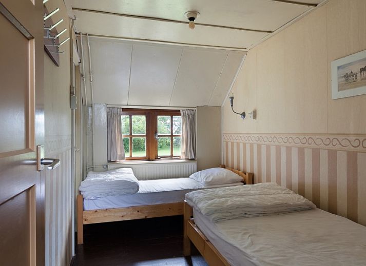 Eetkamer van Meiblok vakantiehuis in Formerum, Terschelling met grote ramen en houten eettafel.