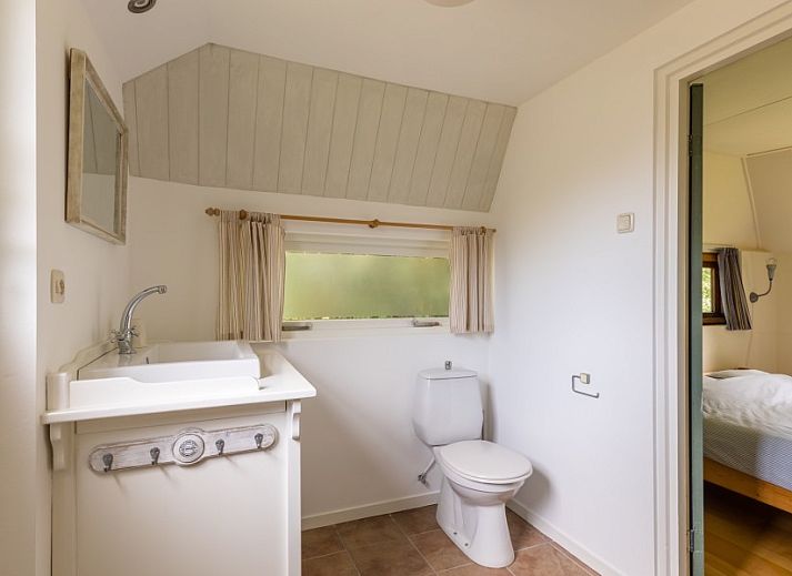 Eetkamer van Meiblok vakantiehuis in Formerum, Terschelling met grote ramen en houten eettafel.