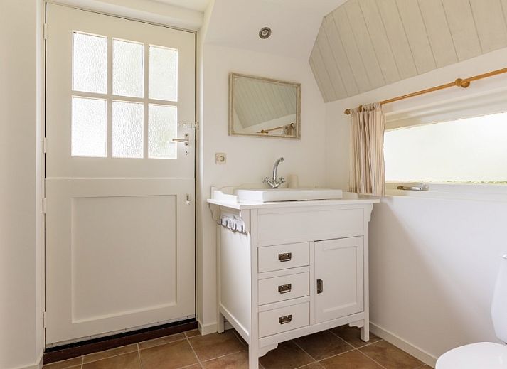 Eetkamer van Meiblok vakantiehuis in Formerum, Terschelling met grote ramen en houten eettafel.