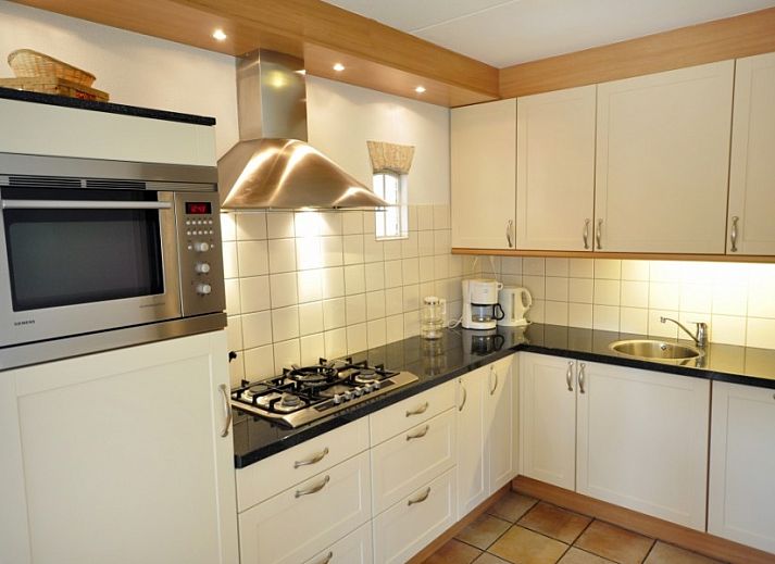 Flaches Bauernhaus de Hek West in Hoorn, Terschelling mit einer einladenden Terrasse und gruener Umgebung.