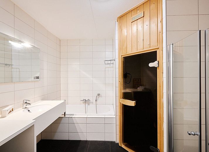 Gezellige woonkamer in Wellness Appartement | 6 Pers in Midsland, Terschelling met comfortabele zithoek en moderne keuken.
