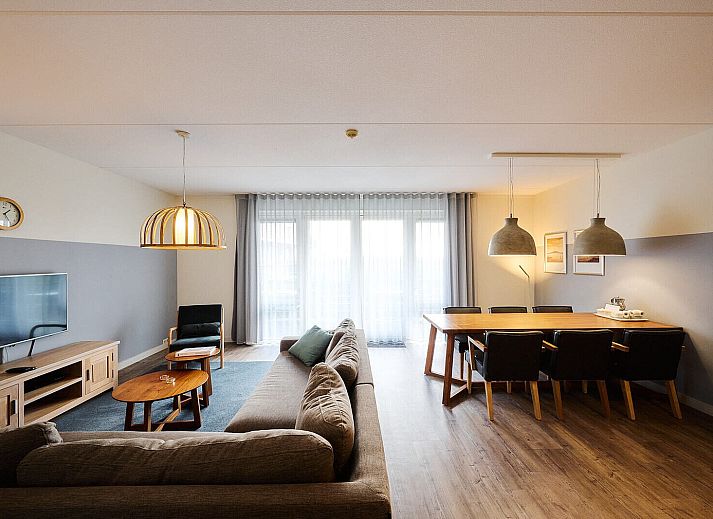 Gezellige woonkamer in Wellness Appartement | 6 Pers in Midsland, Terschelling met comfortabele zithoek en moderne keuken.