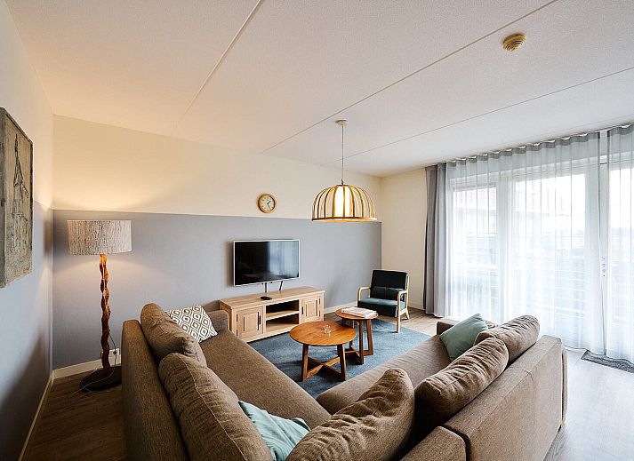 Gezellige woonkamer in Wellness Appartement | 6 Pers in Midsland, Terschelling met comfortabele zithoek en moderne keuken.