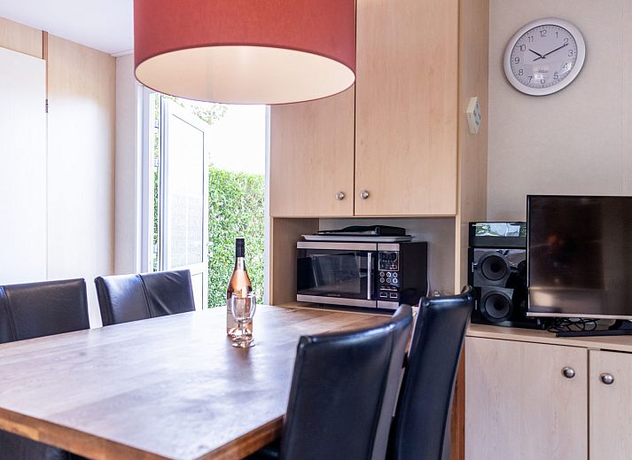 Veranda des Duinbungalows Mindervalide in Oosterend, Terschelling, mit bequemen Stuehlen und Sonnenschirm.