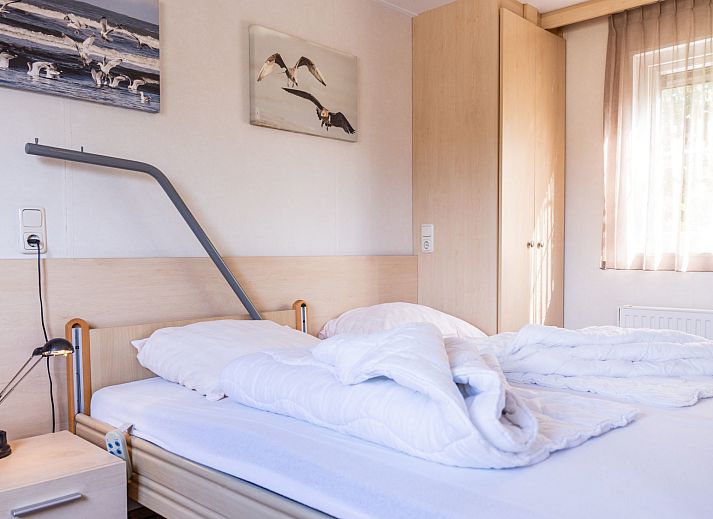 Veranda des Duinbungalows Mindervalide in Oosterend, Terschelling, mit bequemen Stuehlen und Sonnenschirm.