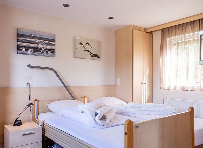 Veranda des Duinbungalows Mindervalide in Oosterend, Terschelling, mit bequemen Stuehlen und Sonnenschirm.