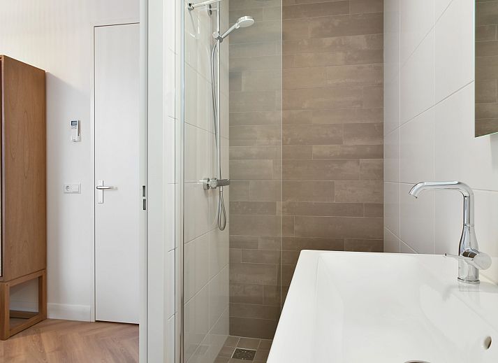 Spacious living room of the 4-person penthouse 4CP in West Terschelling with comfortable sitting area and view of the dunes.