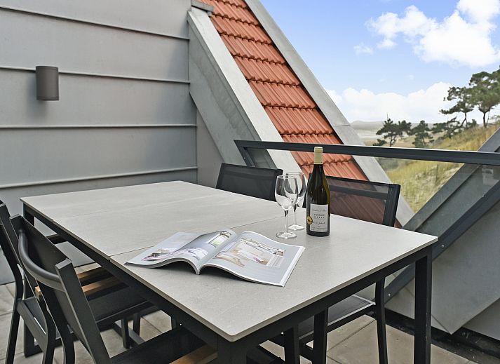 Spacious living room of the 4-person penthouse 4CP in West Terschelling with comfortable sitting area and view of the dunes.