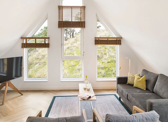 Spacious living room of the 4-person penthouse 4CP in West Terschelling with comfortable sitting area and view of the dunes.