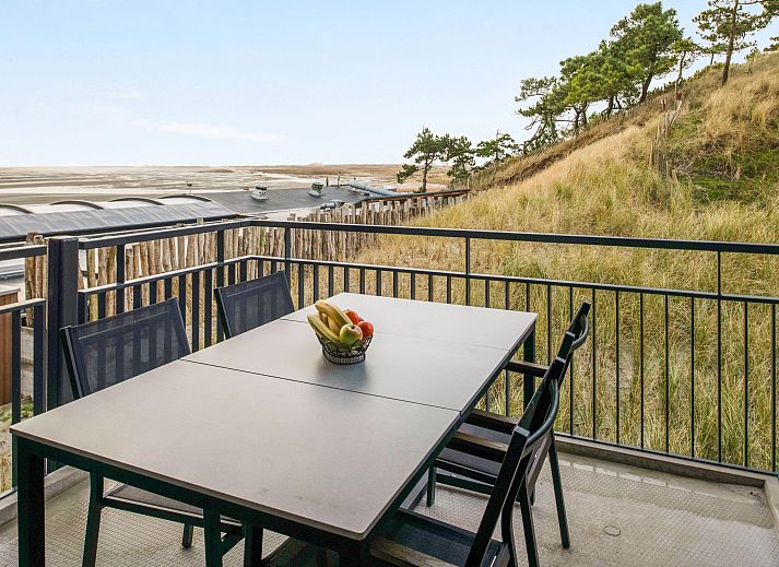 Geraeumiger Balkon der 4-Personen-Wohnung 4L in West Terschelling, mit Blick auf die Duenen und einem Esstisch fuer Mahlzeiten im Freien.
