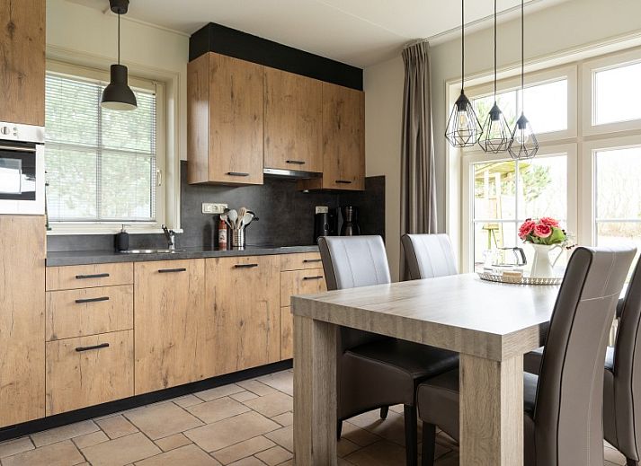 Ferienhaus De Dijkwachter in Ballum, Ameland, umgeben von gruenen Feldern und bunten Blumen.