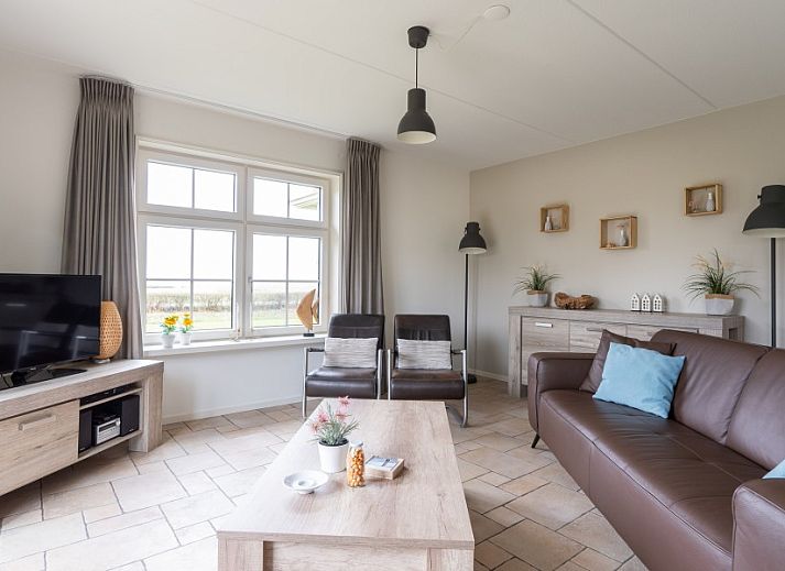 Ferienhaus De Dijkwachter in Ballum, Ameland, umgeben von gruenen Feldern und bunten Blumen.