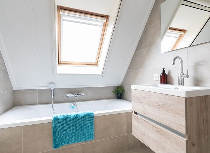 Ferienhaus De Dijkwachter in Ballum, Ameland, umgeben von gruenen Feldern und bunten Blumen.