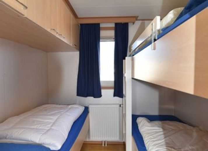 Gezellige woonkamer in chalet Oester 167, Ballum, Ameland met veel natuurlijk licht en comfortabele zitplaatsen.