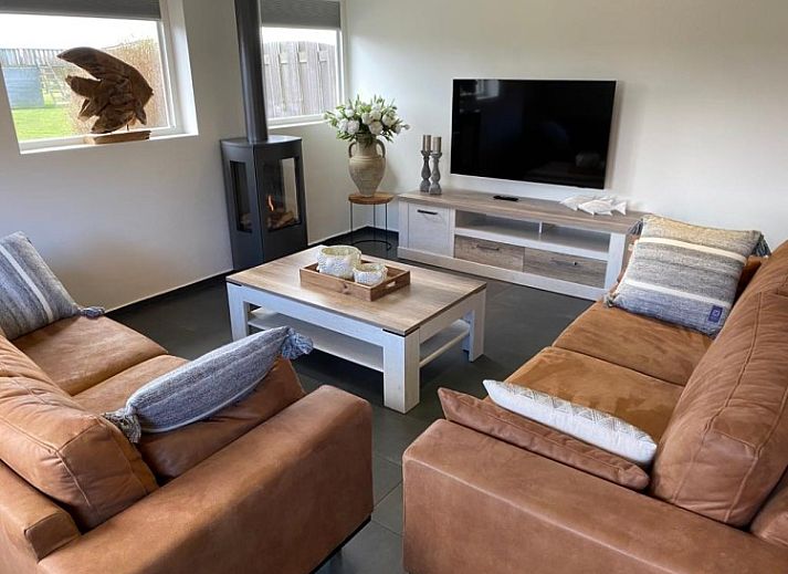 Cozy living room of Tree Lodge in Ballum, Ameland with comfortable sofas and wood stove.