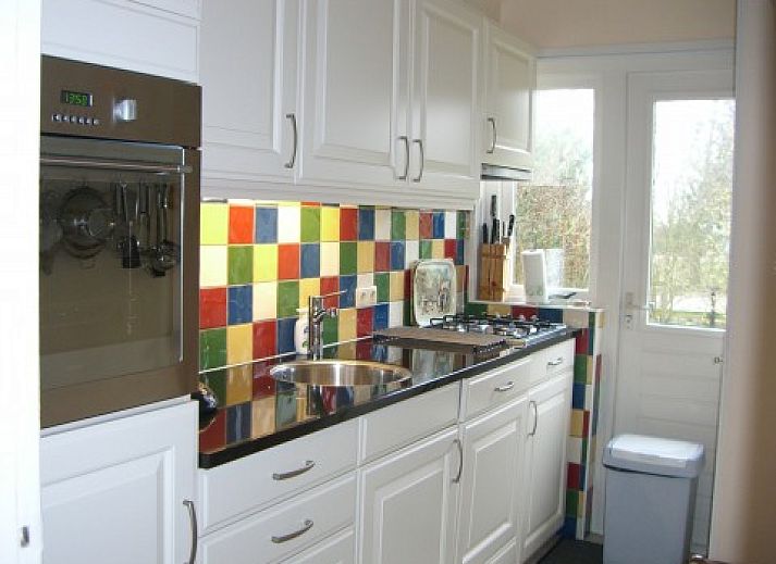 Akkerduin vakantiehuis met rieten dak in Ballum, Ameland, omgeven door groene tuin.